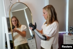 Jessica Smith, a former Australian Paralympic Swimmer, poses for a picture with her new bionic hand that improves the speed of movement and sensitivity of touch, according to the company, in London, Britain August 12, 2022. (REUTERS/Maja Smiejkowska)