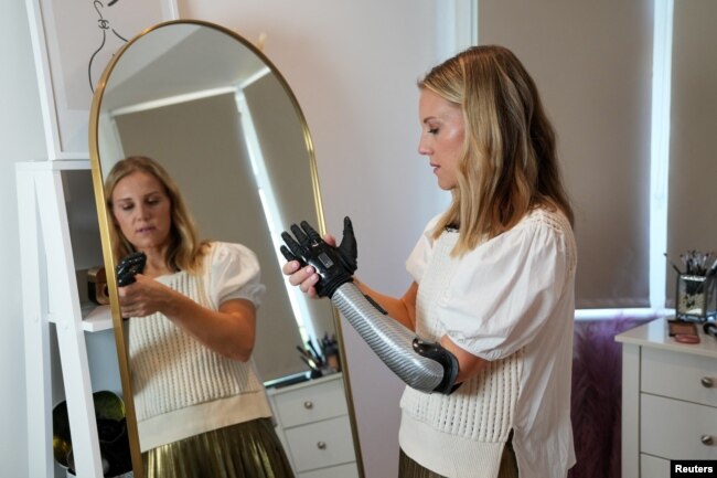 Jessica Smith, a former Australian Paralympic Swimmer, poses for a picture with her new bionic hand that improves the speed of movement and sensitivity of touch, according to the company, in London, Britain August 12, 2022. (REUTERS/Maja Smiejkowska)