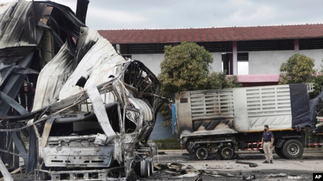 A Thai officer stands beside the burnt down oil tanker at a gas station in Pattani province, southern Thailand, Aug. 17, 2022.