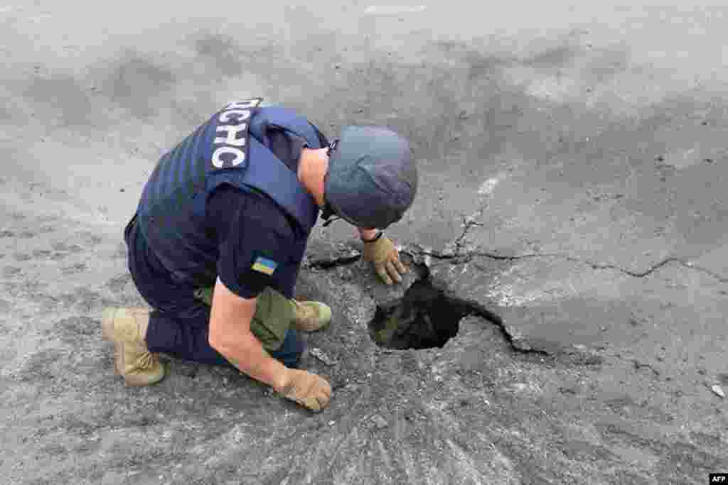 A rescuer examines a crater after a Russian shelling in Kharkiv, amid the Russian military invasion of Ukraine, in this handout picture taken and released by Ukrainian State Emergency Service.