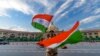 Seorang polisi India mengibarkan dengan bendera India di depan gedung legislatif negara bagian Uttar Pradesh selama persiapan perayaan Hari Kemerdekaan di lucknow, India, Kamis, 11 Agustus 2022. (Foto: AP/Rajesh Kumar Singh)