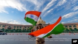 Seorang polisi India mengibarkan dengan bendera India di depan gedung legislatif negara bagian Uttar Pradesh selama persiapan perayaan Hari Kemerdekaan di lucknow, India, Kamis, 11 Agustus 2022. (Foto: AP/Rajesh Kumar Singh)