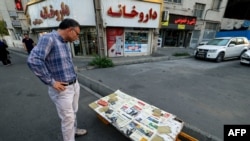 A man looks at a newspaper stall with a view of Etemad newspaper's front page bearing a title reading in Farsi 'The night of the end of the JCPOA ', in the capital Tehran on Aug. 16, 2022.