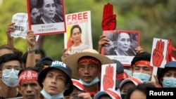 FILE - Demonstrators hold placards with pictures of Aung San Suu Kyi as they protest against the military coup in Yangon, Myanmar, Feb. 22, 2021. 