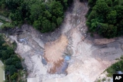 In this aerial photo, a community reservoir that ran nearly empty after its retaining wall started to leak and hot weather and drought conditions accelerated the loss of water is seen in Longquan village in southwestern China's Chongqing Municipality, Saturday, Aug. 20, 2022.