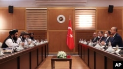 FILE - Turkish Foreign Minister Mevlut Cavusoglu, right, and Amir Khan Muttaqi, the acting foreign minister, of Afghanistan, left, speak during a meeting, in Ankara, Turkey, Thursday, Oct. 14, 2021. 