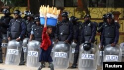 A woman walks past police officers as Angola&#39;s election commission says ruling MPLA party leads with 52% majority, after the general election closes in Luanda.