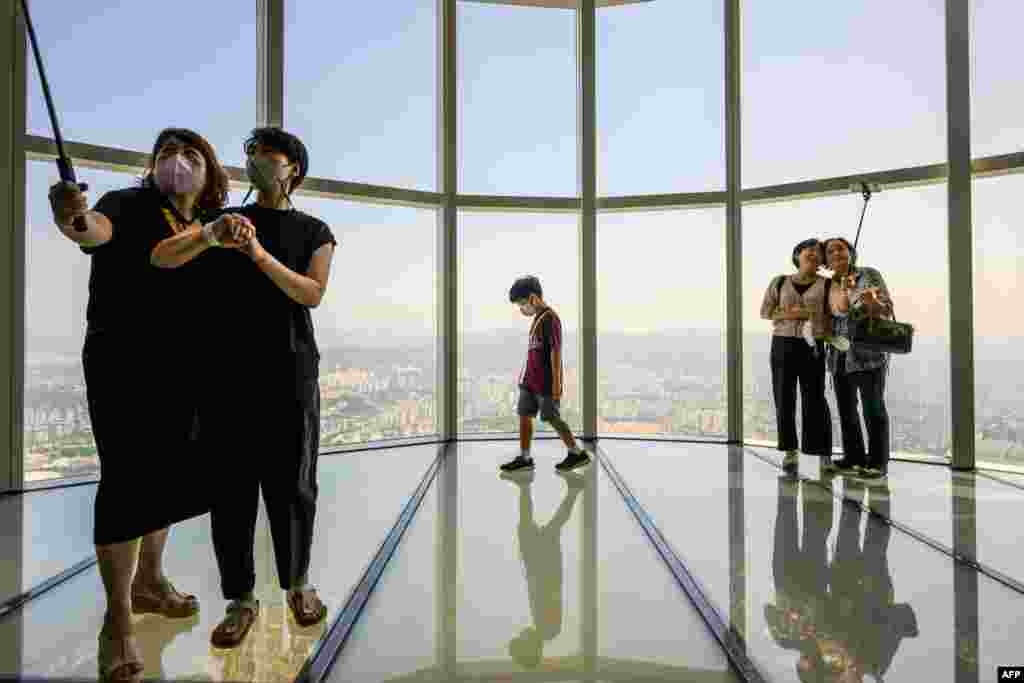 Visitors take selfies as a young boy walks on the observation deck at the Lotte World Tower Seoul Sky in Seoul, South Korea.