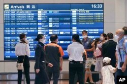 Beberapa orang mengenakan masker di tengah pandemi COVID-19, di aula kedatangan di bandara Haneda di Tokyo, Jepang, 23 Agustus 2022. (Kyodo News via AP)