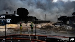 Los bomberos se paran en el lugar de un incendio mortal en una gran instalación de almacenamiento de petróleo en Matanzas, Cuba, el martes 9 de agosto de 2022. (Yamil Lage, vía AP)