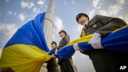 In this photo provided by the Ukrainian Presidential Press Office, honour guard soldiers prepare to rise the Ukrainian national flag during State Flag Day celebrations in Kyiv, Ukraine, Aug. 23, 2022.