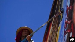 Mexican artist Jesus Rodriguez paints the finishing touches on a mural he is painting on the facade of an auditorium in San Salvador, Mexico, July 30, 2022.