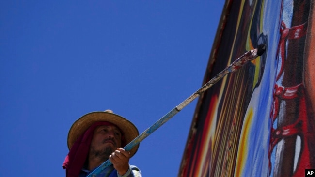 Mexican artist Jesus Rodriguez paints the finishing touches on a mural he is painting on the facade of an auditorium in San Salvador, Mexico, July 30, 2022.
