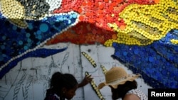Voluntarios usan tapas de botellas para un colorido eco-mural creado por el artista venezolano Oscar Olivares para crear conciencia sobre el reciclaje, en Caracas, Venezuela, 19 de agosto de 2022. REUTERS/Gaby Oraa