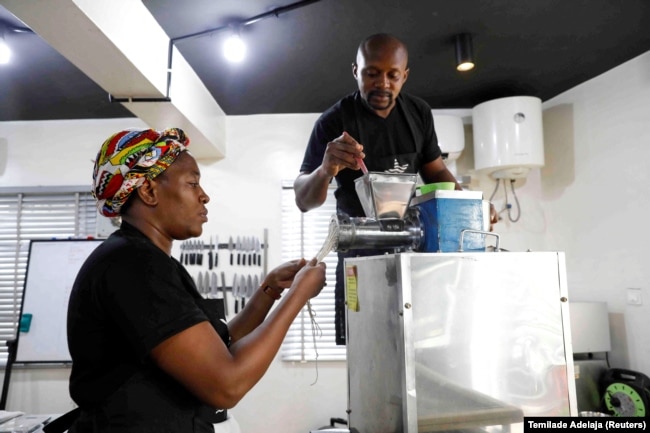 Renee Chuks, alongside a staff member, prepares fresh cassava pasta at their production kitchen in Ikeja, Lagos, Nigeria June 21, 2022.