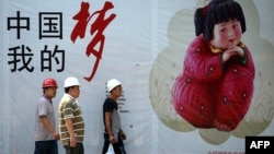 幾名中國工人走過北京街頭張貼的中國夢宣傳畫。（2013年9月2日）