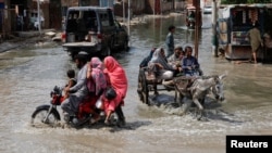 Ciudadanos viajan en medio de las inundaciones dejadas por las lluvias e inundaciones en Jacobabad, Pakistán, el 30 de agosto de 2022.