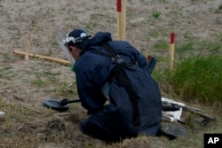 A mine detection worker with the HALO Trust de-mining NGO searches for anti-tank and anti personnel land mines in Lypivka, on the outskirts of Kyiv, Ukraine, June 14, 2022.