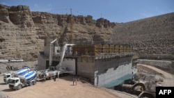 FILE - In this photograph taken on March 21, 2021, laborers work on the construction of a powerhouse at the hydroelectric Kajaki Dam in Kajaki, northeast of Helmand Province. The second phase of the dam's construction was completed by the Turkish company 77 Construction.