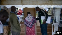 Seorang perempuan menandai surat suaranya di bilik suara sebuah tempat pemungutan suara di Kisumu, Kenya, 9 Agustus 2022. (Brian ONGORO / AFP)