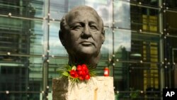 Flowers and a candle are placed at a bust of the former Soviet President Mikhail Gorbachev at the Axel Springer Publisher House in Berlin, Germany, Aug. 31, 2022.