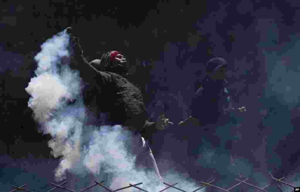 A coca farmer prepares to return a tear gas canister to police during the fourth week of clashes near a coca leaf market in La Paz, Bolivia, Aug. 22, 2022.