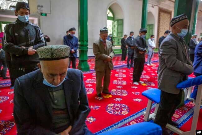 FILE - Uyghurs and other members of the faithful pray during services at the Id Kah Mosque in Kashgar in far west China's Xinjiang region, as seen during a government-organized visit for foreign journalists on April 19, 2021.