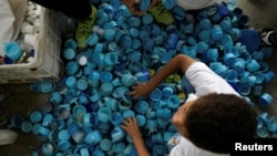La gente clasifica las tapas de las botellas para un colorido mural ecológico creado por el artista venezolano Oscar Olivares para crear conciencia sobre el reciclaje, en Caracas, Venezuela, 19 de agosto de 2022. REUTERS/Gaby Oraa
