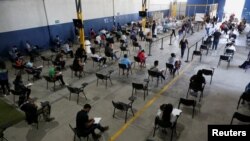 Migrantes, en su mayoría nicaragüenses, llenan papeles en un centro de migración mientras esperan una entrevista con funcionarios del gobierno para solicitar asilo en Costa Rica debido a la situación política de su país, en San José, Costa Rica, 10 de enero de 2022.