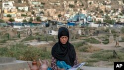 Sara, 14, duduk di kuburan dan membaca buku sambil menjual air di pemakaman di Kabul, 30 Juli 2022. (AP Photo/Ebrahim Noroozi)