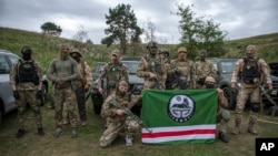 Volunteer soldiers pose with a flag of the Chechen Republic of Ichkeria after training near Kyiv, Ukraine, Aug. 27, 2022. Volunteers have signed up to fight on both sides of the conflict.
