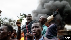 Supporters of Kenya's Azimio La Umoja Party (One Kenya Coalition Party) presidential candidate Raila Odinga react past burning tyres during a protest against the results of Kenya's general election in Kibera, Nairobi, western Kenya on August 15, 2022. 