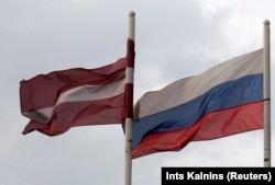 Bendera Latvia (kiri) berkibar tertiup angin di samping bendera Rusia di dekat sebuah hotel di Daugavpils pada 21 Maret 2014. (Foto: REUTERS/Ints Kalnins)