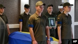 Ukrainian servicemen stand guard next to coffin of activist Julia Chaika during a funeral service in Zaporizhzhia, Ukraine, Aug. 21, 2022. Julia Chaika was killed fighting Russian forces on Aug. 18. 
