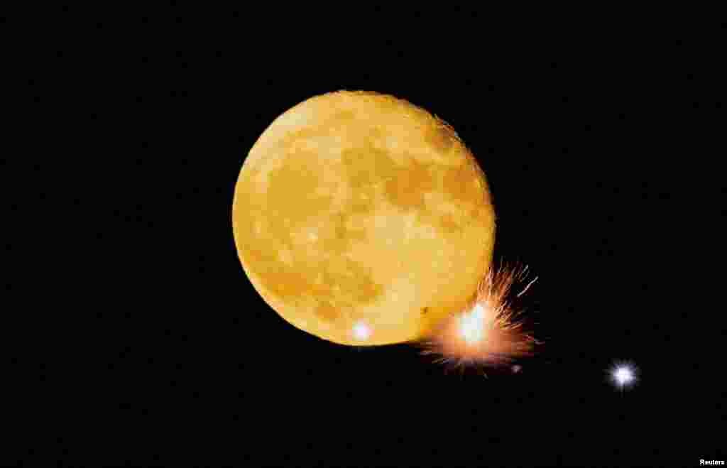 Petards explode in front of the waning moon during a fireworks display in Mqabba, Malta, Aug. 13, 2022. 