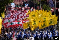Pramuka Syiah Lebanon dari kelompok Hizbullah yang didukung Iran, membawa bendera kelompok mereka dan bendera Lebanon saat berbaris dalam peringatan Ashoura, di pinggiran selatan Beirut, Lebanon, Selasa, Agustus 9, 2022. (AP/Hussein Malla)