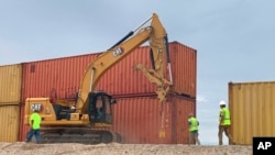 This photo provided by the Arizona governor's office shows shipping containers that will be used to fill a 1,000-foot gap in the border wall with Mexico near Yuma, Ariz., Aug. 12, 2022.