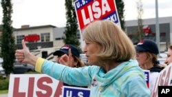 La senadora estadounidense Lisa Murkowski, republicana de Alaska, muestra un pulgar hacia arriba a un automovilista que pasa mientras agita carteles, el martes 16 de agosto de 2022, en Anchorage, Alaska.