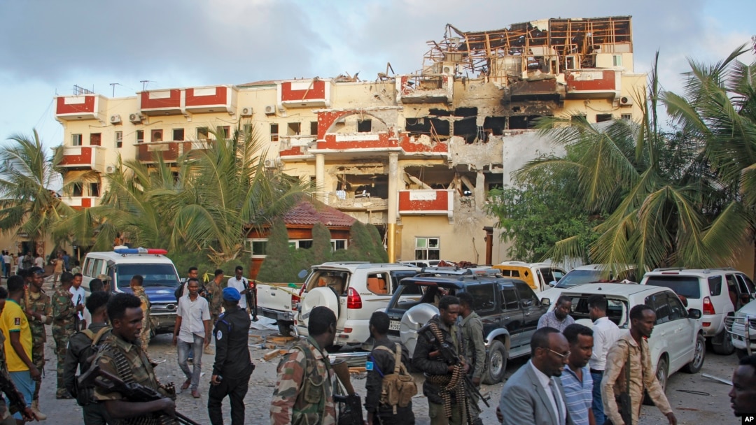 Security forces and others walk in front of the damaged Hayat Hotel in the capital Mogadishu, Somalia, Aug. 21, 2022. 