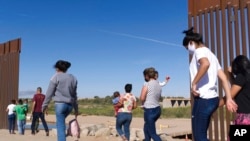 FILE - Brazilian migrants make their way around a gap in the U.S.-Mexico border in Yuma, Ariz., seeking asylum in the U.S. after crossing over from Mexico, June 8, 2021. 