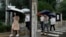 Office workers walk with umbrellas during a rainy day in Beijing, Aug. 18, 2022. Some were killed with others missing after a flash flood in western China Thursday, as China faces both summer rains and severe heat and drought in different parts of the country.