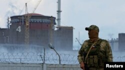 FILE - A serviceman with a Russian flag on his uniform stands guard near the Zaporizhzhia Nuclear Power Plant in the course of Ukraine-Russia conflict outside the Russian-controlled city of Enerhodar in the Zaporizhzhia region, Ukraine, Aug. 4, 2022. 