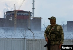 FILE - A serviceman with a Russian flag on his uniform stands guard near the Zaporizhzhia Nuclear Power Plant outside the Russian-controlled city of Enerhodar in Ukraine's Zaporizhzhia region, Aug. 4, 2022.