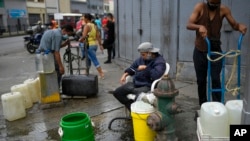 Los residentes aprovechan una boca de incendios para llenar sus recipientes con agua en el barrio de San Juan de Caracas, Venezuela, el martes 19 de enero de 2021, en medio de la pandemia del nuevo coronavirus.