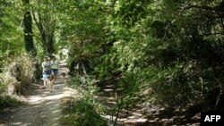 Two women walk their dogs along the Thames footpath, beside the dry River Thames (on the right), near the English village of Ashton Keynes, on Aug. 8, 2022.