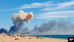 Rising smoke can be seen from the beach at Saky after explosions were heard from the direction of a Russian military airbase near Novofedorivka, Crimea, Aug. 9, 2022.