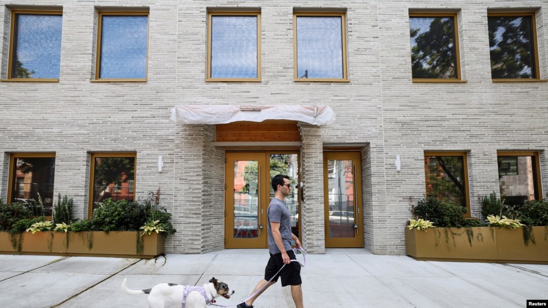 A man walks his dog past Timber House, the city's first mass-timber condo building, in New York City, Aug. 16, 2022.