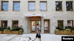 A man walks his dog past Timber House, the city's first mass-timber condo building, in New York City, Aug. 16, 2022.