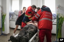 FILE - Ukrainian paramedic Serhiy Chornobryvets, center, with his colleagues treat a man wounded by shelling in a hospital in Mariupol, Ukraine, March 1, 2022.
