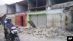 Residents on a motorcycle pass a damaged building after a 6.7 magnitude in the town of Bima, on Indonesia's Sumbawa island, Nov. 9, 2009. The island was struck by two earthquakes, Jan. 22, 2019, of magnitude 6 and 6.6.